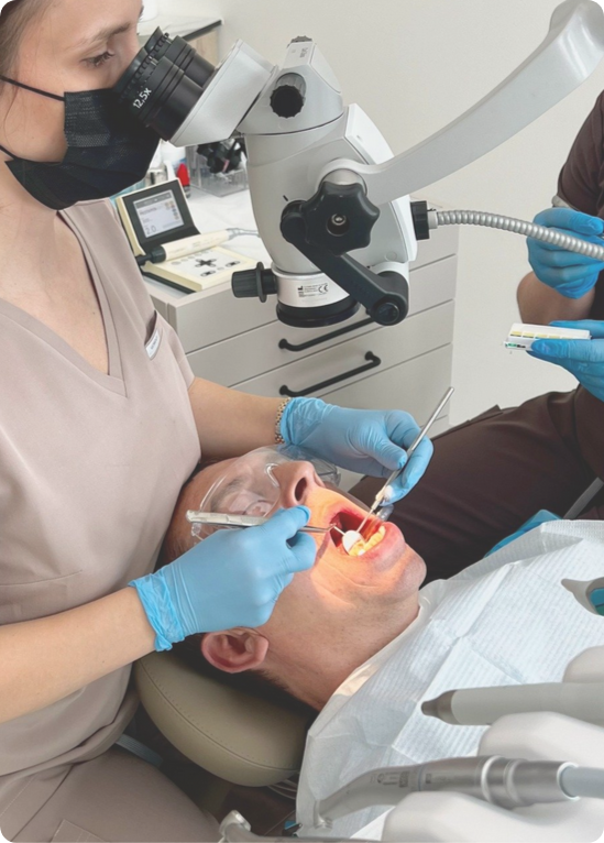 Dentysta wykonujący precyzyjne leczenie kanałowe pod mikroskopem w klinice Ortocraft w Radomiu. Endodoncja mikroskopowa i ratowanie zębów.